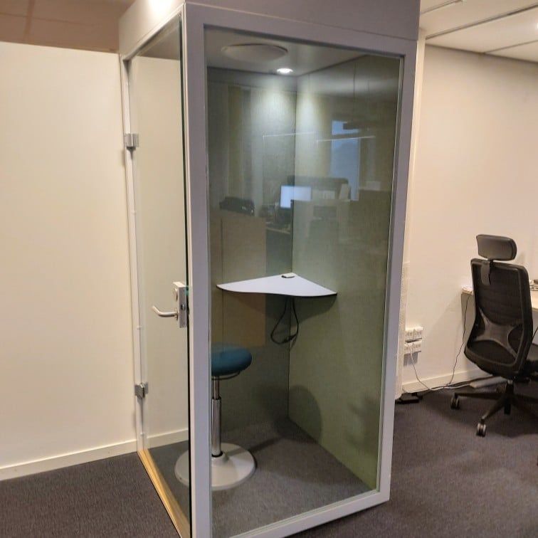 Begagnad telefonbås med vit stomme gröna innerväggar och glasdörr. Med pall och hörnbord. Mått: Bredd 100 cm, Djup 100 cm, Höjd 230 cm. 