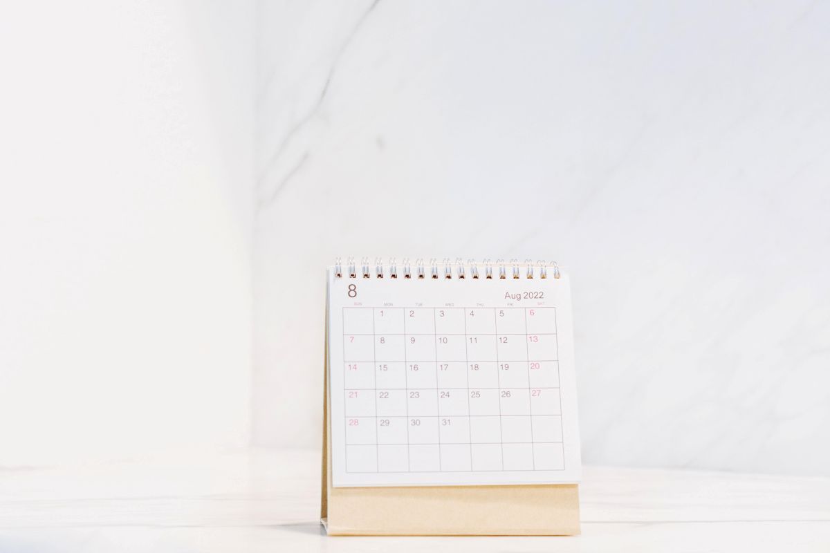 Stående kalender på en vit yta mot en vägg i vit marmor med text om att man kan boka en demo.