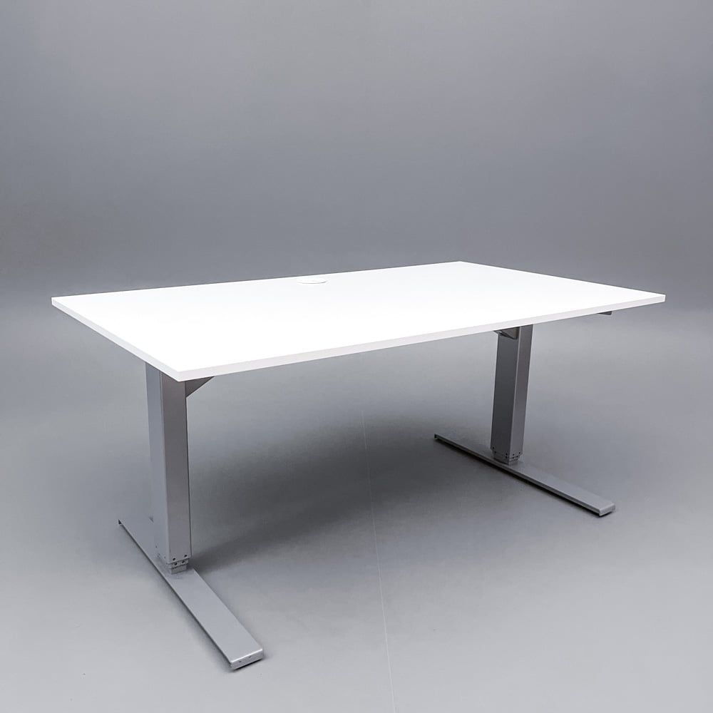 Begagnat höj- och sänkbart skrivbord med kabeldike. I vitt med stativ i silver. Mått: Bredd 140 cm, djup 80 cm, höjd justerbar mellan 70 till 120 cm.