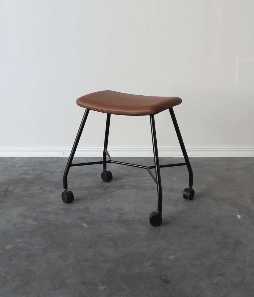 Begagnad pall på hjul Motus från Materia. Sits klädd i brunt läder, svart stativ. Mått: bredd 53 cm, djup 37 cm, höjd 48 cm. 