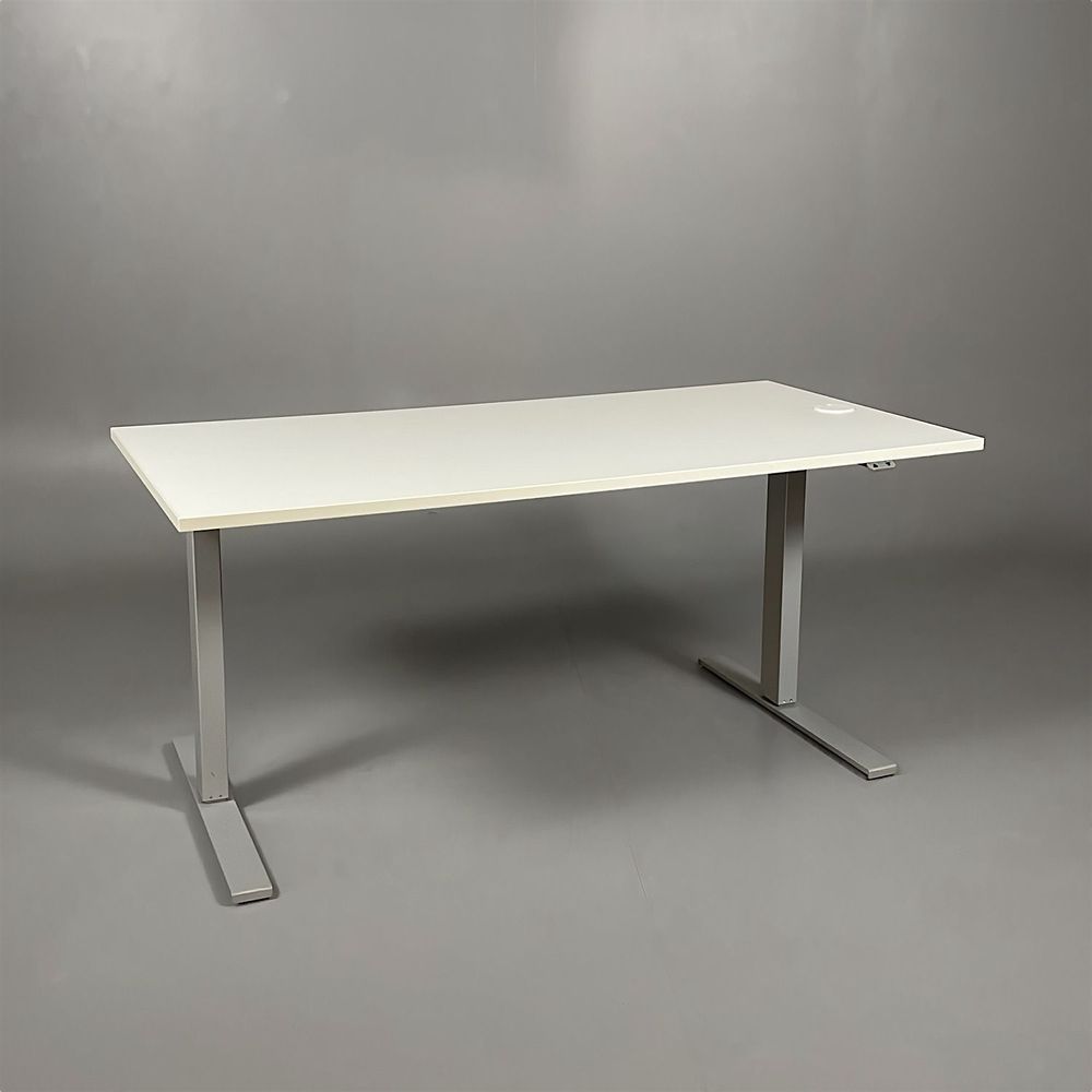 Begagnat höj & sänkbart skrivbord, rektangulärt i vit färg, med silverstativ. Mått: Bredd 160 x Djup 80 x Höjd 70–120 cm. Inkluderar kabelhål.
