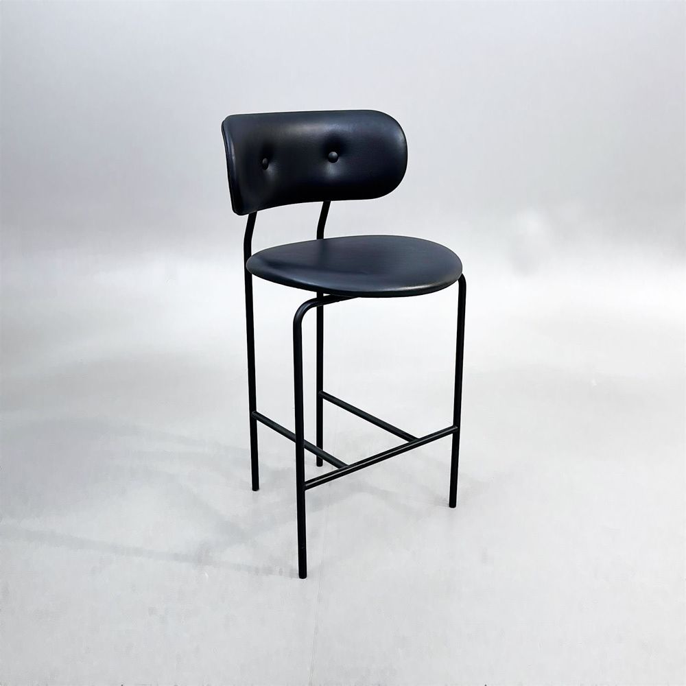 Begagnad barstol Coco från GUBI i svart läder med svartlackerade ben, ryggstöd och integrerat fotstöd. Mått: Bredd 51 cm, djup 52 cm, höjd 98 cm och sitthöjd 65 cm.