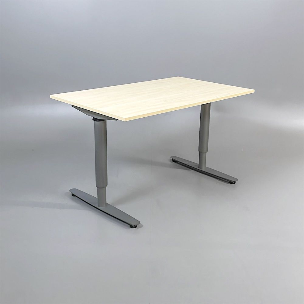 Begagnat höj-och-sänkbart skrivbord. Bordsskivan är rektangulär och gjord av björklaminat, kombinerad med ett silverstativ. Mått bredd 130 cm, djup 80 cm, Höjd 70-120 cm.