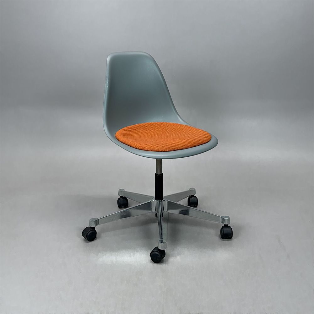 Begagnad stol med hjul Eames Plastic Side Chair PSCC från Vitra i grå plast med orange sittdyna, kromat underrede. Mått: Bredd 46,5 cm, djup 55 cm, höjd 76–88,5 cm. 