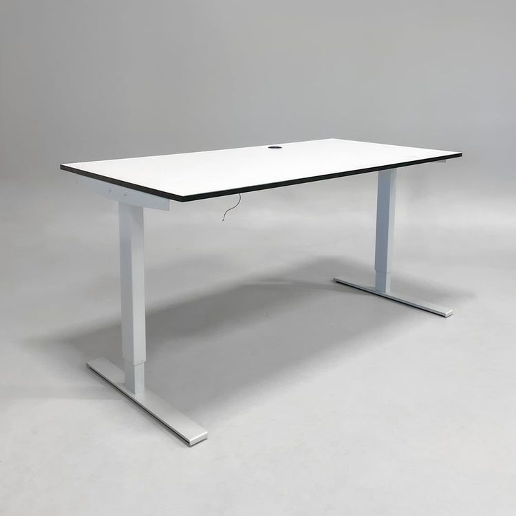 Begagnat höj- och sänkbart skrivbord med vit bordsskiva svart kant och silverfärgade ben. Mått: bredd 110 cm och djup 90 cm, Justerbar höjd 70 - 120 cm. 