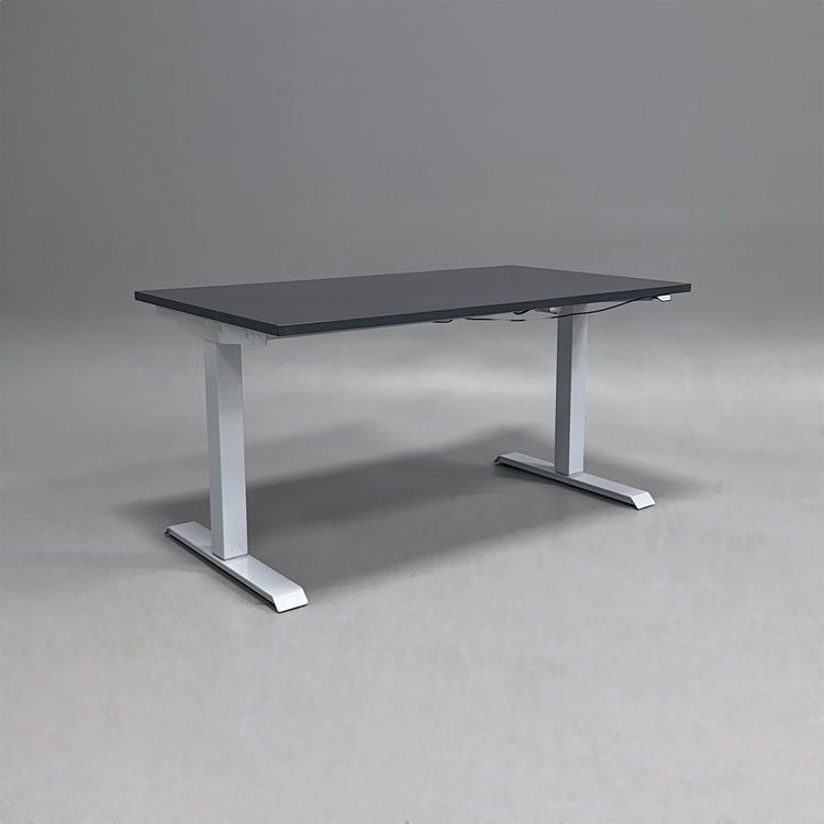 Begagnat höj- och sänkbart skrivbord med mörkgrå bordsskiva och silverfärgat stativ. Mått: bredd 140 cm, djup 80 cm med justerbar höjd 70 - 120 cm. 