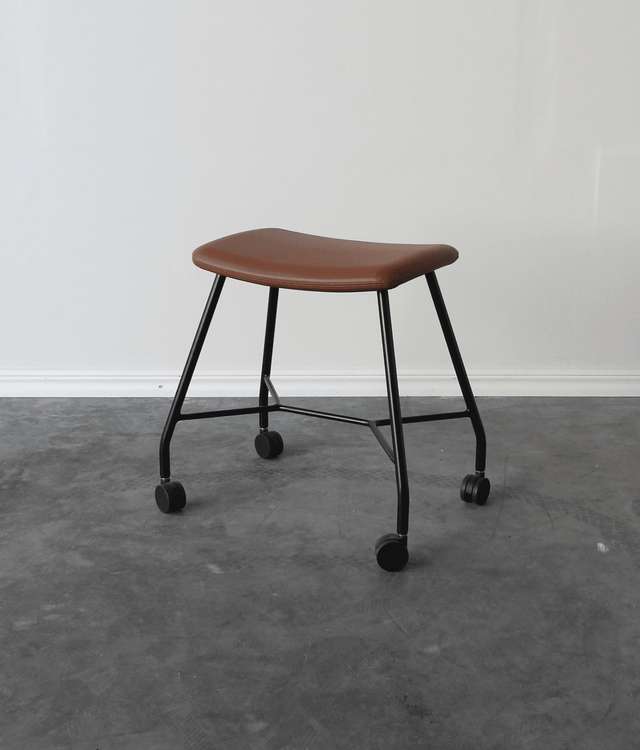 Begagnad pall på hjul Motus från Materia. Sits klädd i brunt läder, svart stativ. Mått: bredd 53 cm, djup 37 cm, höjd 48 cm. 