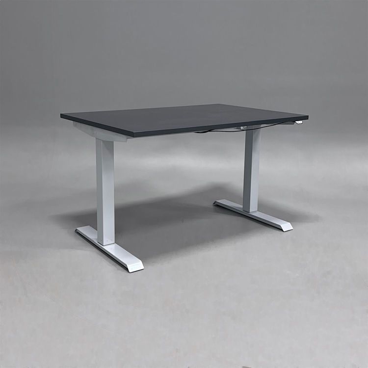 Begagnat höj och sänkbart skrivbord med mörkgrå bordsskiva oxh silvrigt stativ. Mått: bredd 120 cm, djup 80 cm, höjd 70 - 120 cm.