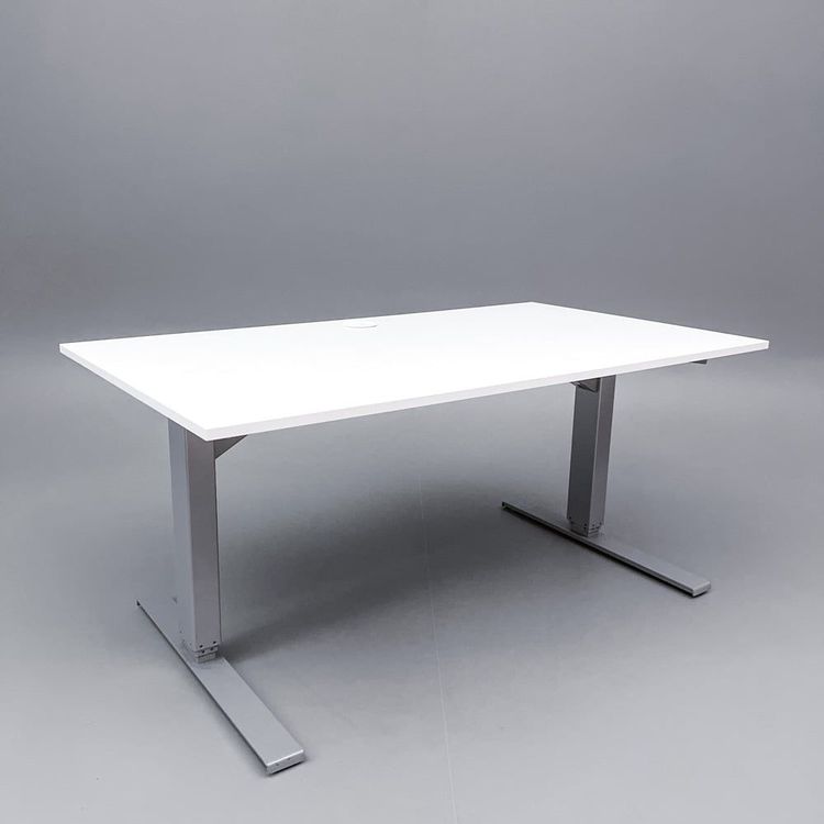Begagnat höj- och sänkbart skrivbord med kabeldike. I vitt med stativ i silver. Mått: Bredd 140 cm, djup 80 cm, höjd justerbar mellan 70 till 120 cm. 