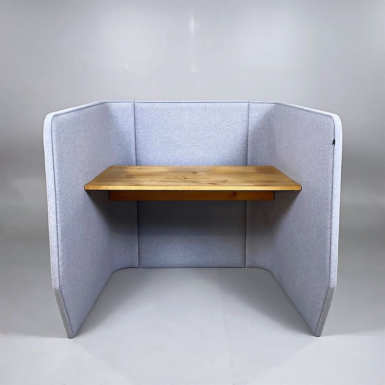 Begagnat arbetsbås i grått från BuzziSpace med stoppade väggar och ett integrerat bord i ek. Mått: bredd 130 cm, djup 110 cm och höjd 120 cm.