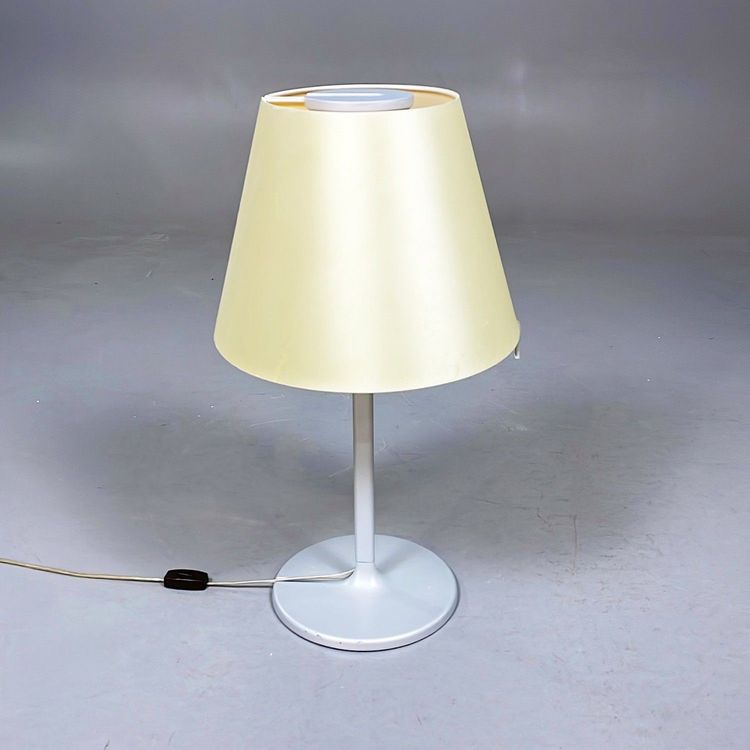 Begagnad bordslampa Melampo från Artemide i beige färg och silverstativ. Mått: Diameter 35 cm, höjd justerbar mellan 63 till 86 cm.