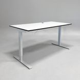 Begagnat höj- och sänkbart skrivbord med vit bordsskiva svart kant och silverfärgade ben. Mått: bredd 110 cm och djup 90 cm, Justerbar höjd 70 - 120 cm. 