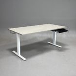 Begagnat höj och sänkbart skrivbord i med ljusgrått bordsskiva och vitt stativ. Mått: Bredd 160 cm, Djup 80 cm, Höjd justerbar från 70 till 120 cm. 