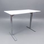 Begagnat höj- och sänkbart skrivbord med kabeldike. I vitt med stativ i silver. Mått: Bredd 140 cm, djup 80 cm, höjd justerbar mellan 70 till 120 cm. 