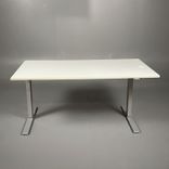 Begagnat höj & sänkbart skrivbord, rektangulärt i vit färg, med silverstativ. Mått: Bredd 160 x Djup 80 x Höjd 70–120 cm. Inkluderar kabelhål.