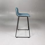 Begagnad barstol Neo från Materia med blågrön klädsel, svart underrede och integrerat fotstöd. Mått: bredd 55 cm, djup 46 cm, höjd 83 cm, sitthöjd 63 cm. 
