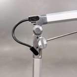 Begagnad skrivbordslampa Lucy från Erco i silverfärg. Mått: Bredd 73 cm, Höjd 67 cm. 