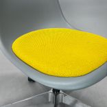 Begagnad stol med hjul Eames Plastic Side Chair PSCC från Vitra i ljusgrå plast med gul sittdyna, kromat underrede. Mått: Bredd 46,5 cm, djup 55 cm, höjd 76–88,5 cm. 