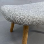 En begagnad grå fotpall/sittpuff AAL03 Ottoman från HAY i ljusgrått och ben av ek. Mått: bredd 66 cm, djup 50 cm och höjd 32 cm.  