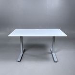 Begagnat höj och sänkbart skrivbord med vit bordsskiva och silverstativ. Mått: Bredd 140 cm, Djup 80 cm, Höjd justerbar mellan 70 cm till 120 cm. 