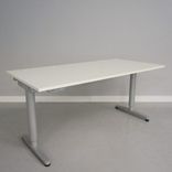 Begagnat höj- och sänkbart skrivbord Galant från Ikea. Laminatskiva i vitt med silverfärgat stativ. Mått: Bredd 160 cm, Djup 80 cm, Höjd justerbar mellan 70 till 120 cm. 