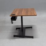 Begagnat höj och sänkbart skrivbord med bordsskiva i laminat finish av valnöt, stativ i  svart. Mått: bredd 100 cm, djup 70 cm, justerbar höjd mellan 64 till 115 cm. 