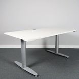 Begagnat höj- och sänkbart skrivbord Serie T från Kinnarps. Med vit laminatskiva samt silverfärgat stativ. Mått bredd 140 cm, djup 80 cm, höjd 62 - 128 cm. 