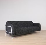 Begagnad 3-sits soffa Mega från Massproductions. Mått: längd 230 cm, höjd 78 cm. Med runda sidopaneler av vitt stål som omger och lyfter de svartmönstrade dynorna. 