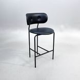 Begagnad barstol Coco från GUBI i svart läder med svartlackerade ben, ryggstöd och integrerat fotstöd. Mått: Bredd 51 cm, djup 52 cm, höjd 98 cm och sitthöjd 65 cm. 