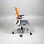 Begagnad kontorsstol från Steelcase, modell Think. Med sits i mörkgrått och rygg i orange mesh. Mått: Justerbar sitthöjd 41 till 53 cm. 