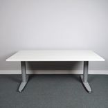Begagnat höj- och sänkbart skrivbord Serie T från Kinnarps. Bordsskiva i vitt med stativ i silver. Mått: bredd 160 cm, djup 80 cm, Höjd 61.5 cm till 128 cm. 