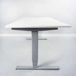Begagnat höj och sänkbart skrivbord, med rektangulär vit bordsskiva och silvrigt stativ. Mått: Bredd: 160 cm, Djup: 80 cm, Justerbar höjd: 70–120 cm. 