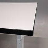 Begagnat höj- och sänkbart skrivbord från Rekomo med mått på bredd 159 cm, djup 80 cm och justerbar höjd mellan 70 till 120 cm. Bordsskivan är vit med svarta kanter samt ett silverfärgat stativ. Praktiskt elstativ.