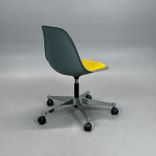Begagnad stol med hjul Eames Plastic Side Chair PSCC från Vitra i ljusgrå plast med gul sittdyna, kromat underrede. Mått: Bredd 46,5 cm, djup 55 cm, höjd 76–88,5 cm. 