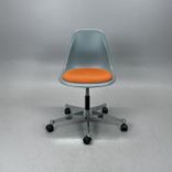 Begagnad stol med hjul Eames Plastic Side Chair PSCC från Vitra i grå plast med orange sittdyna, kromat underrede. Mått: Bredd 46,5 cm, djup 55 cm, höjd 76–88,5 cm. 