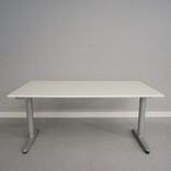 Begagnat höj- och sänkbart skrivbord Galant från Ikea. Laminatskiva i vitt med silverfärgat stativ. Mått: Bredd 160 cm, Djup 80 cm, Höjd justerbar mellan 70 till 120 cm. 