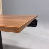 Begagnat höj och sänkbart skrivbord med bordsskiva i laminat finish av valnöt, stativ i  svart. Mått: bredd 100 cm, djup 70 cm, justerbar höjd mellan 64 till 115 cm. 