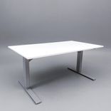 Begagnat höj- och sänkbart skrivbord med kabeldike. I vitt med stativ i silver. Mått: Bredd 140 cm, djup 80 cm, höjd justerbar mellan 70 till 120 cm. 
