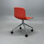Begagnad stol med hjul AAC15 från HAY. Med tegelröd tygklädsel och kromat kryssunderrede. Mått: Bredd 51 cm, djup 52 cm, höjd 77 cm och sitthöjd 46 cm. 