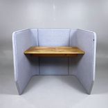 Begagnat arbetsbås i grått från BuzziSpace med stoppade väggar och ett integrerat bord i ek. Mått: bredd 130 cm, djup 110 cm och höjd 120 cm. 