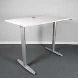 Begagnat höj- och sänkbart skrivbord Serie T från Kinnarps. Med vit laminatskiva samt silverfärgat stativ. Mått bredd 140 cm, djup 80 cm, höjd 62 - 128 cm. 