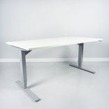 Begagnat höj och sänkbart skrivbord, med rektangulär vit bordsskiva och silvrigt stativ. Mått: Bredd: 160 cm, Djup: 80 cm, Justerbar höjd: 70–120 cm. 