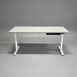 Begagnat höj och sänkbart skrivbord i med ljusgrått bordsskiva och vitt stativ. Mått: Bredd 160 cm, Djup 80 cm, Höjd justerbar från 70 till 120 cm. 