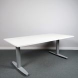 Begagnat höj- och sänkbart skrivbord Serie T från Kinnarps. Bordsskiva i vitt med stativ i silver. Mått: bredd 160 cm, djup 80 cm, Höjd 61.5 cm till 128 cm. 