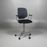 Begagnad stol med hjul från Savo, Invite High i mörkgrå/svart färg. Stolen har svängbara hjul, armstöd, justerbar sitthöjd mellan 65 till 85 centimeter och ett kromat underrede. Den erbjuder bra komfort för långa sessioner.